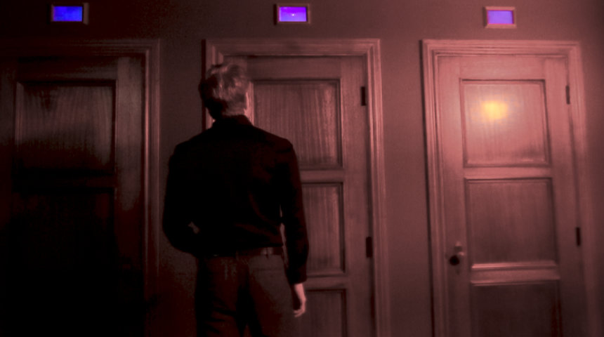 a person standing in front of 3 wood doors