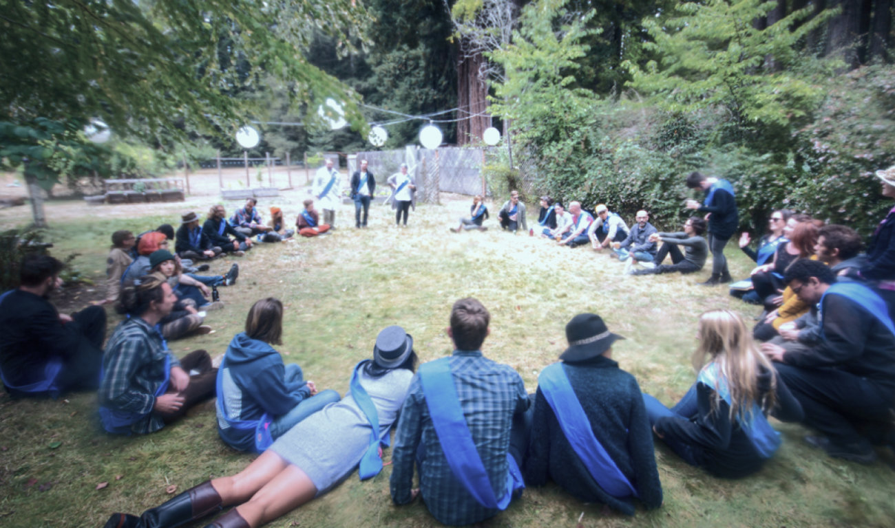 members sitting in a circle on the grass